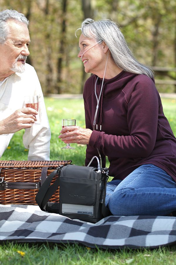 OxyGo NEXT NG portable oxygen concentrator in its carrying case at a picnic